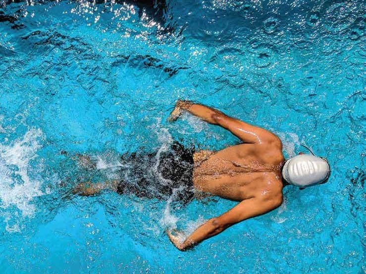 A swimmer doing laps in a bright blue pool