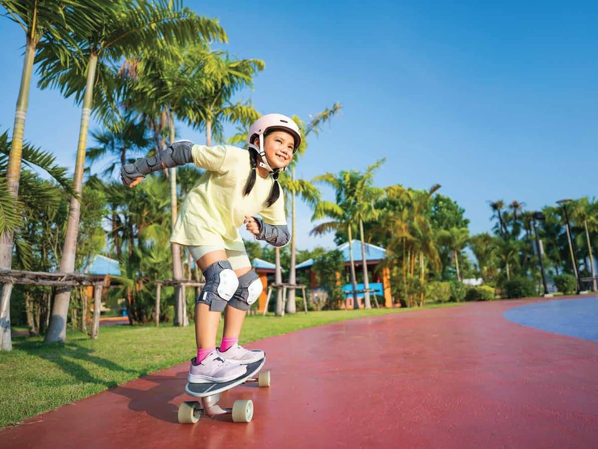 A girl skateboarding along a palm-lined track